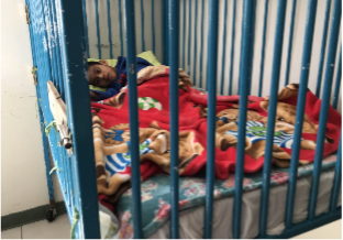 A boy lying down in a crib with rails