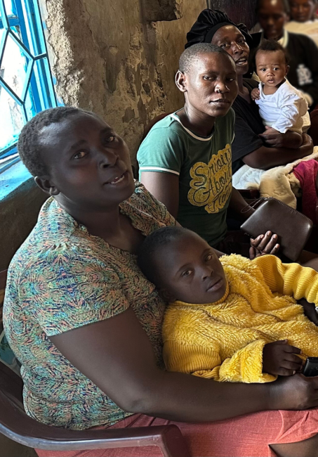 Women sit together holding young children and babies on their laps