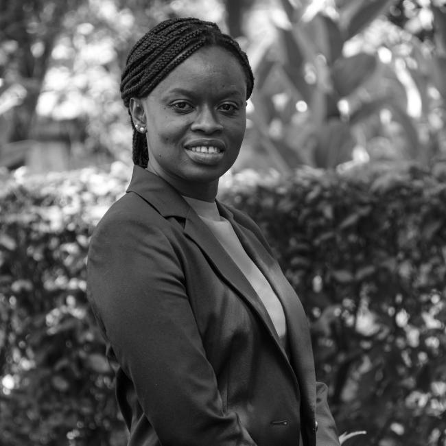 A woman in business attire stands outdoors, smiling